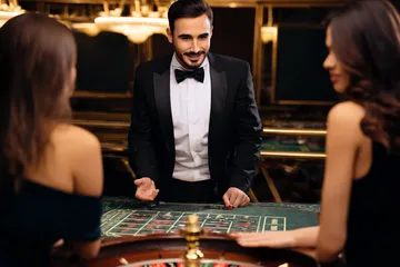 A professional dealer in a tuxedo greeting players at the roulette table, symbolizing the authentic live casino feel at D71.